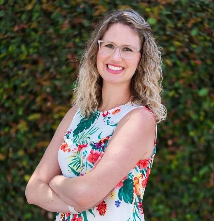 Briana Sampson, Licensed Marriage & Family Therapist, smiling in front of a green hedge